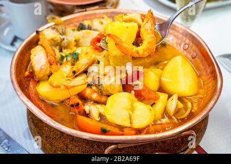 Traditional portuguese dish Cataplana cooked and served in a domed copper pot. Lisbon Stock Photo