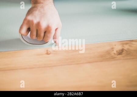 Laying laminate - bonding sheets of foam polystyrene with adhesive tape Stock Photo