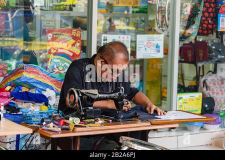 A man repairs clothes with an old fashioned cast-iron sewing machine, Bangkok, Thailand. Stock Photo