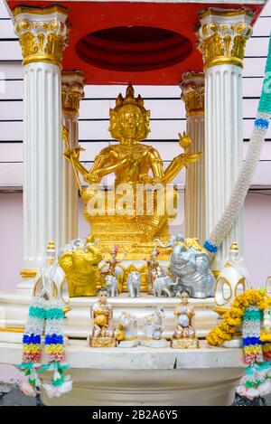 Golden multi-faced buddha statue in a shrine with orange flowers, Bangkok, Thailand Stock Photo