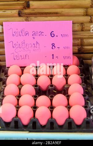 Pink century eggs with a price list in Thai, at a street food market stall, Thailand Stock Photo