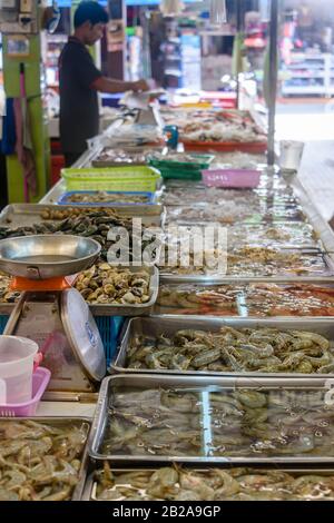 Seafood including prawns, shrimp, clams, sea snails, squid, octopus and green lipped mussels for sale at a Thai fishmonger food market stall, Thailand Stock Photo