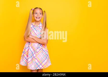 Photo of pretty funny small lady arms crossed good mood look playful side empty space wear checkered plaid summer dress isolated yellow shine color Stock Photo