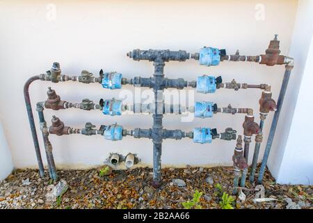 Water pipes with water taps and water meters on wall of house Stock Photo