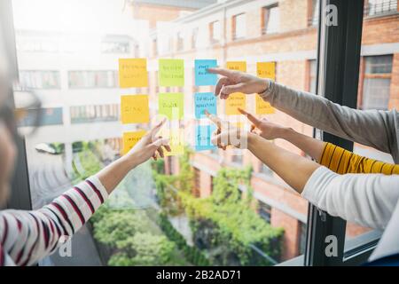 Business people meeting at office and use post notes to share idea. Brainstorming concept. Sticky note on glass wall. Stock Photo