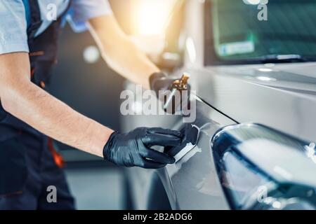 Car detailing - Man applies nano protective coating to the car. Selective focus. Stock Photo