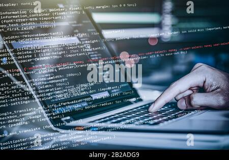 Hacker using laptop. Lots of digits on the computer screen. Stock Photo
