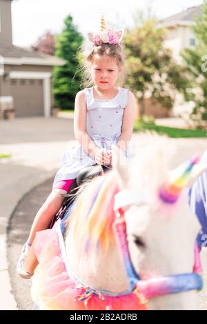 Little girl riding a unicorn at the little girl birthday party. Stock Photo