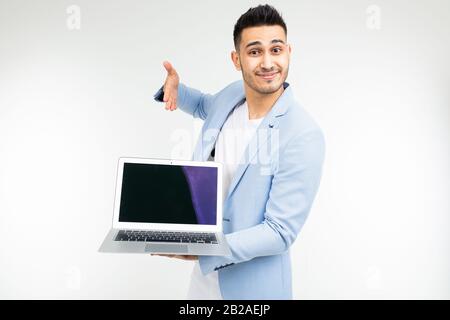 stylish successful man in a jacket demonstrates a laptop screen with space for advertising on a white studio background Stock Photo