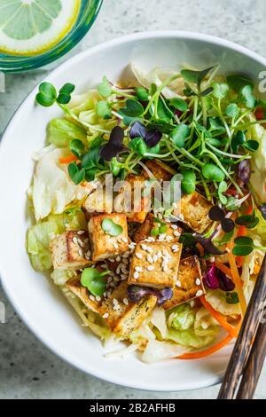 Fried tofu salad with sprouts and sesame seeds in a white bowl. Vegan food, asian food concept. Stock Photo