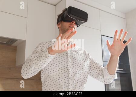 Bearded man wearing virtual reality goggles in modern coworking studio. Smartphone using with VR headset. Horizontal, blurred Stock Photo
