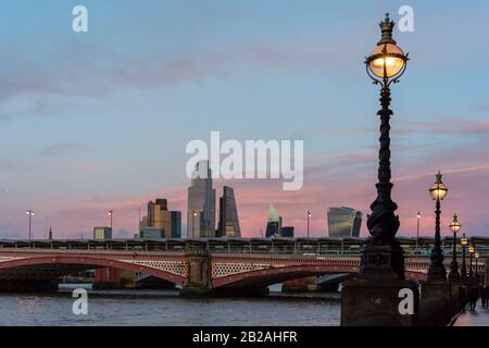 City of London financial district and Blackfriars Bridge view at dusk with Victorian lamps and lights as seen from South the Bank, London, UK as of 2020 Stock Photo