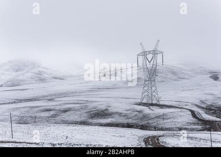 electricity pylon on a mountain which covered with snow Stock Photo