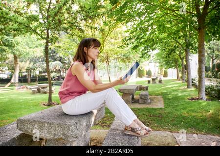 woman reading a book sitting in a park. Concept of leisure, education Stock Photo