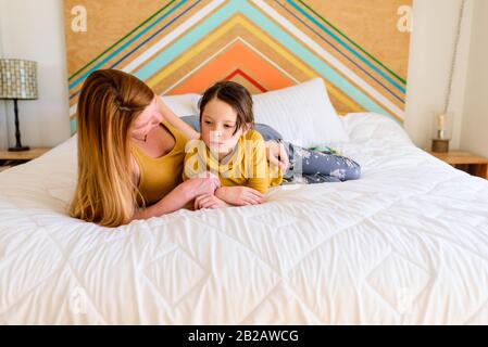 Portrait of a mother and daughter lying on a bed talking Stock Photo
