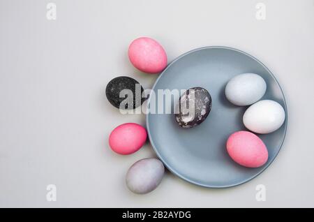 Colorful textured easter eggs on blue plate and near it. Unusual version. Eggs painted with natural pigments. Flat lay Stock Photo