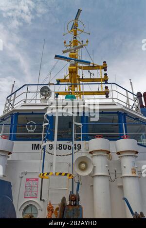 Looking up at the wheelhouse and Vessel Navigation Mast of a small Offshore Supply Vessel sailing in West Africa. Stock Photo