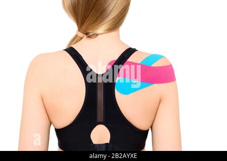 Studio shot of a female patient with kinesio tape on her shoulder and back, isolated over white. Kinesiology, physical therapy, rehabilitation backgro Stock Photo