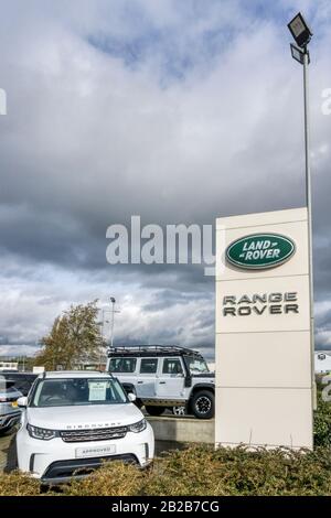 A Land Rover Discovery, with Defender in background, on forecourt of Land Rover Range Rover dealership. Stock Photo