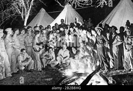 US actress Dorothy Lamour (middle) sings songs around a campfire with a group of American soldiers in Hawaii. Stock Photo