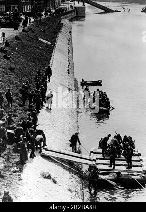 Invasion of Holland 1940: Picture shows vehicles and soldiers crossing the Meuse with boats and in the back the destroyed Wilhelminen-Bridge. Stock Photo