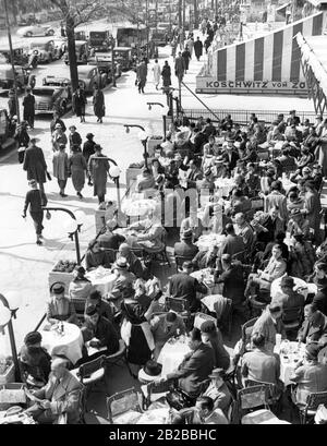 The street cafe Kranzler on Kurfuerstendamm in Berlin is very popular. The photo is showing the terrace of the cafe. To the left of the cafe, passers-by walk along the sidewalk. Stock Photo