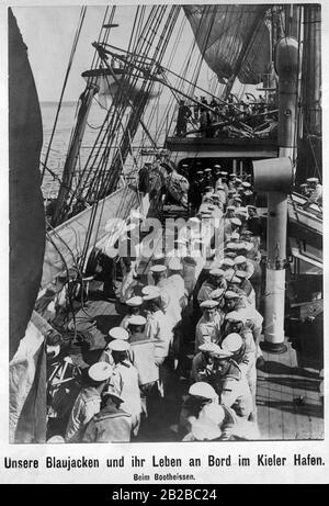 The crew on board a German warship in the naval port of Kiel pull a dinghy into its position. Stock Photo