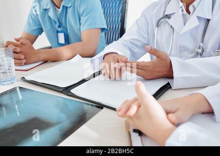 Hands of doctors having urgent meeting and discussing epidemic situation and spread of dangerous virus in country Stock Photo