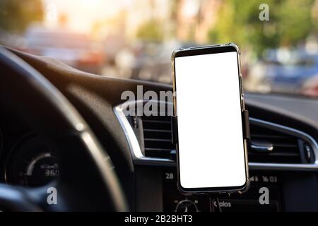 Modern smartphone device gadget mounted on phone holder at car dashboard. Mock-up white screen isolated template. Copyspace for text . Vehicle Stock Photo