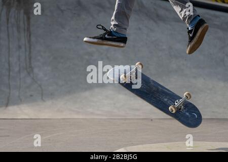 Vienna, Austria - 02/16/2020: Legs of a skateboarder jumping with his skateboard in midair Stock Photo