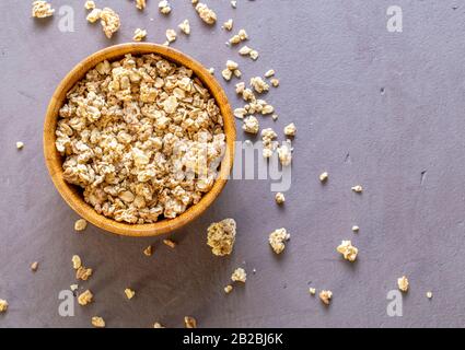 Granola in a wooden bamboo bowl, top view. Scattered granola on table surface. Copy space for text. Stock Photo