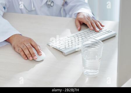 Close-up image of general practitioner working on computer at his office desk Stock Photo