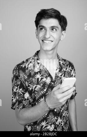 Young handsome Persian teenage boy wearing Hawaiian shirt against gray background Stock Photo