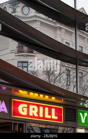 Vienna, Austria - 02/29/2020: Reflection of an old house on a modern building in Wien Landstrasse, red sign of a shop Stock Photo