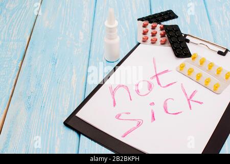 Medical pills against background, the inscription on the sheet not sick Stock Photo