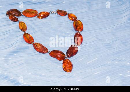 Amber necklace on a light blue background, jewelry made of natural amber Stock Photo