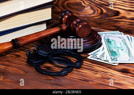Judge's gavel with handcuffs on the background of dollar bills Stock Photo