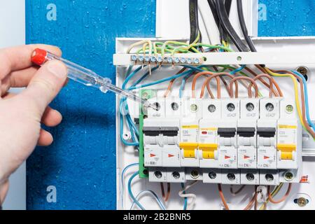 Hand of an electrician with multimeter probe at an electrical switchgear cabinet. Stock Photo