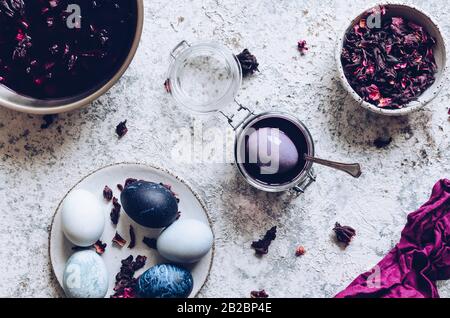 Dyed Easter eggs with marble stone effect painted with natural dye carcade tea from hibiscus flowers on grey concrete background. Top view. Stock Photo
