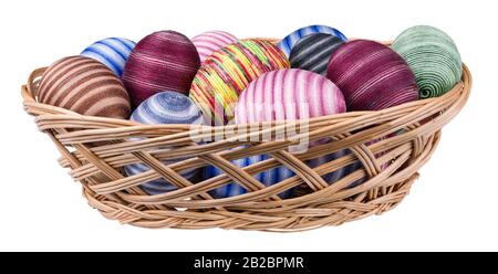 Easter eggs decorated by cotton thread in wicker basket isolated on a white background. Streaked egg shells wrapped by glued thin colored sewing yarn. Stock Photo