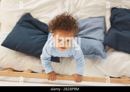 Top view at baby boy looking up while playing on bed, copy space Stock Photo
