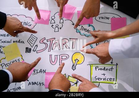 Startup diversity teamwork brainstorming meeting concept. Close up hand of business creative staff presentation with organize chart diagram and work f Stock Photo