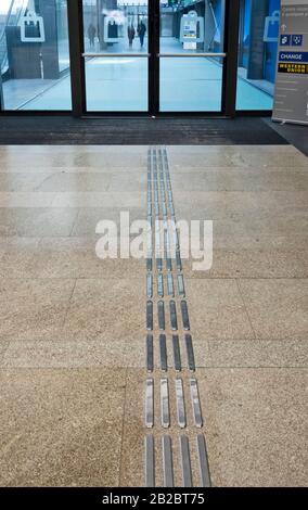 Blind pedestrian walking and detecting markings on tactile paving with textured ground surface indicators for blind and visually impaired. Stock Photo