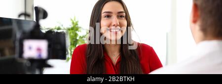 Young woman manager sitting in office and talking with colleague Stock Photo