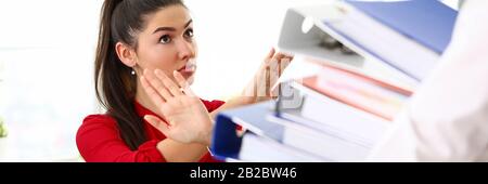 Young happy woman sitting in office and refusing to work with heap of documents Stock Photo