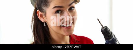 Portrait of young beautiful brunette woman holding holding hammer and drill Stock Photo