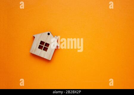 House, insurance and mortgage, buing and rent concept. Small wooden house toy on orange background top view copyspace Stock Photo