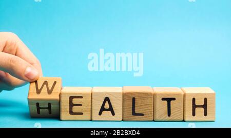 Wooden blocks with the word Health and Wealth. Concept of choosing priority in life and lifestyle. Make the right choice. Life insurance and healthcar Stock Photo