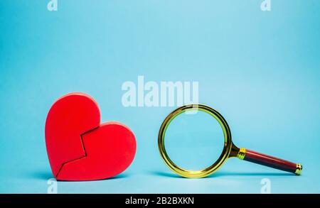 Red heart and a magnifying glass. The concept of finding love and relationships. Find a soul mate. Loneliness. Family psychologist services. Valentine Stock Photo
