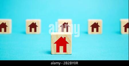 Wooden blocks with a picture of a house. The concept of choosing a place of residence. Best choice of presented options. Purchase of new modern home. Stock Photo